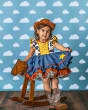 Load image into Gallery viewer, Girl wearing a cowgirl costume dress with checkered bodice, cow print flutter sleeves and full chambray skirt
