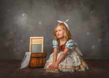 Load image into Gallery viewer, Girl wearing a vintage blue work dress costume with apron, puff sleeves, embroidered pocket, and layered ruffle skirt.