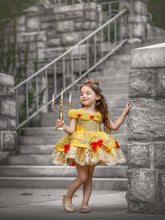 Load image into Gallery viewer, Girl wearing yellow princess dress with gold lace and red bows while holding a gold candelabra
