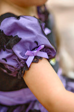 Load image into Gallery viewer, A close-up of a purple and black ruffled costume sleeve with a small lavender ribbon bow and black lace trim.