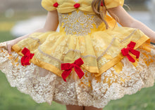 Load image into Gallery viewer, Close-up of yellow princess dress with layered organza skirt, embroidered gold lace and red velvet bows